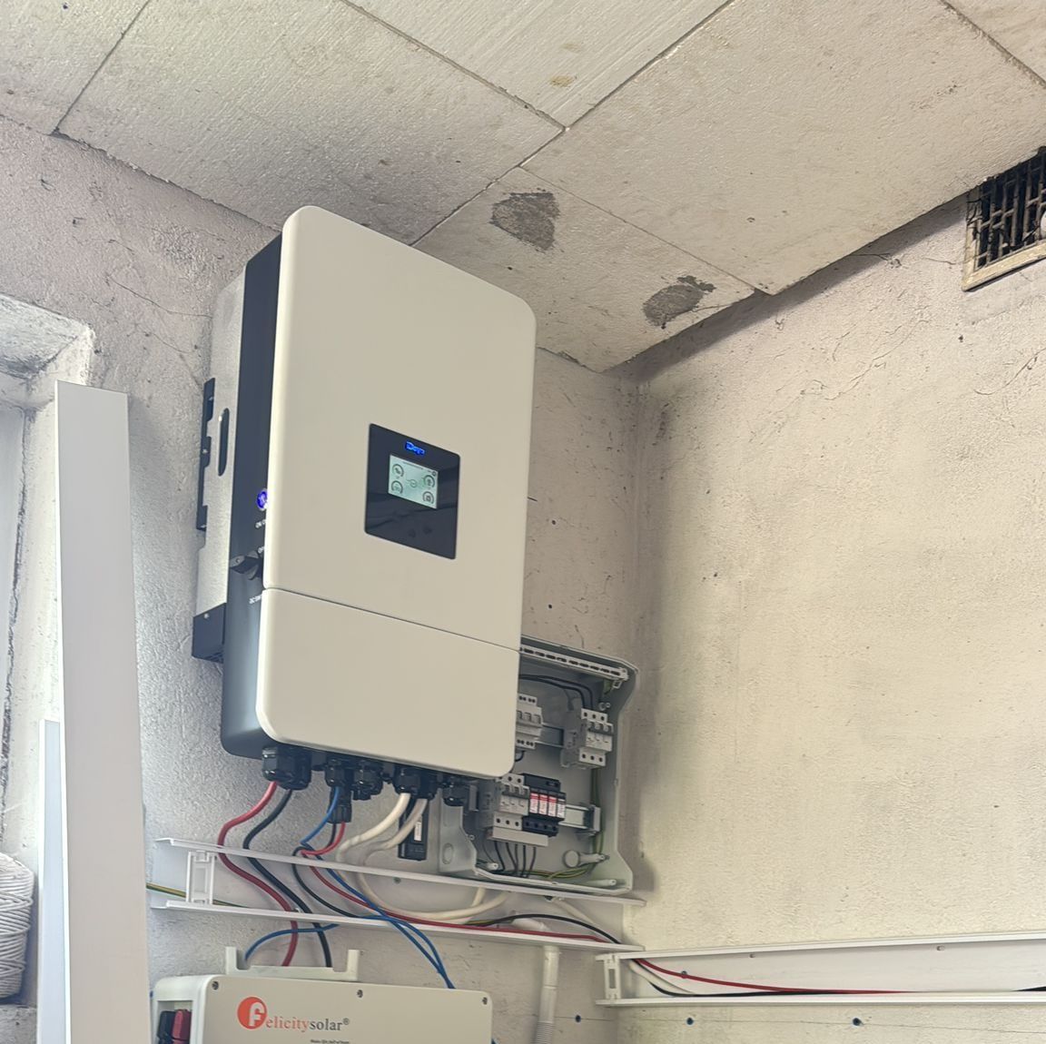 Falownik hybrydowy z rozdzielnicą zamontowany na ścianie pomieszczenia technicznego